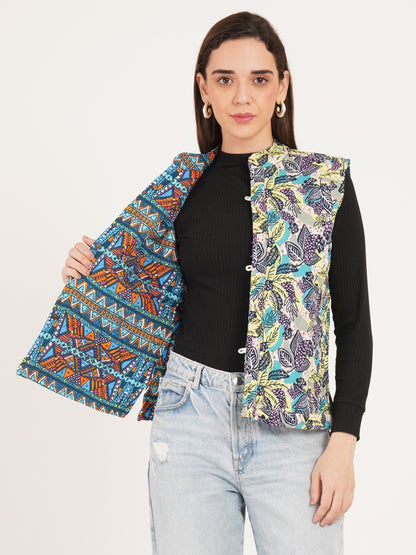 Woman reversible jacket wearing a colorful patterned vest over a black top and light blue jeans on a white background
