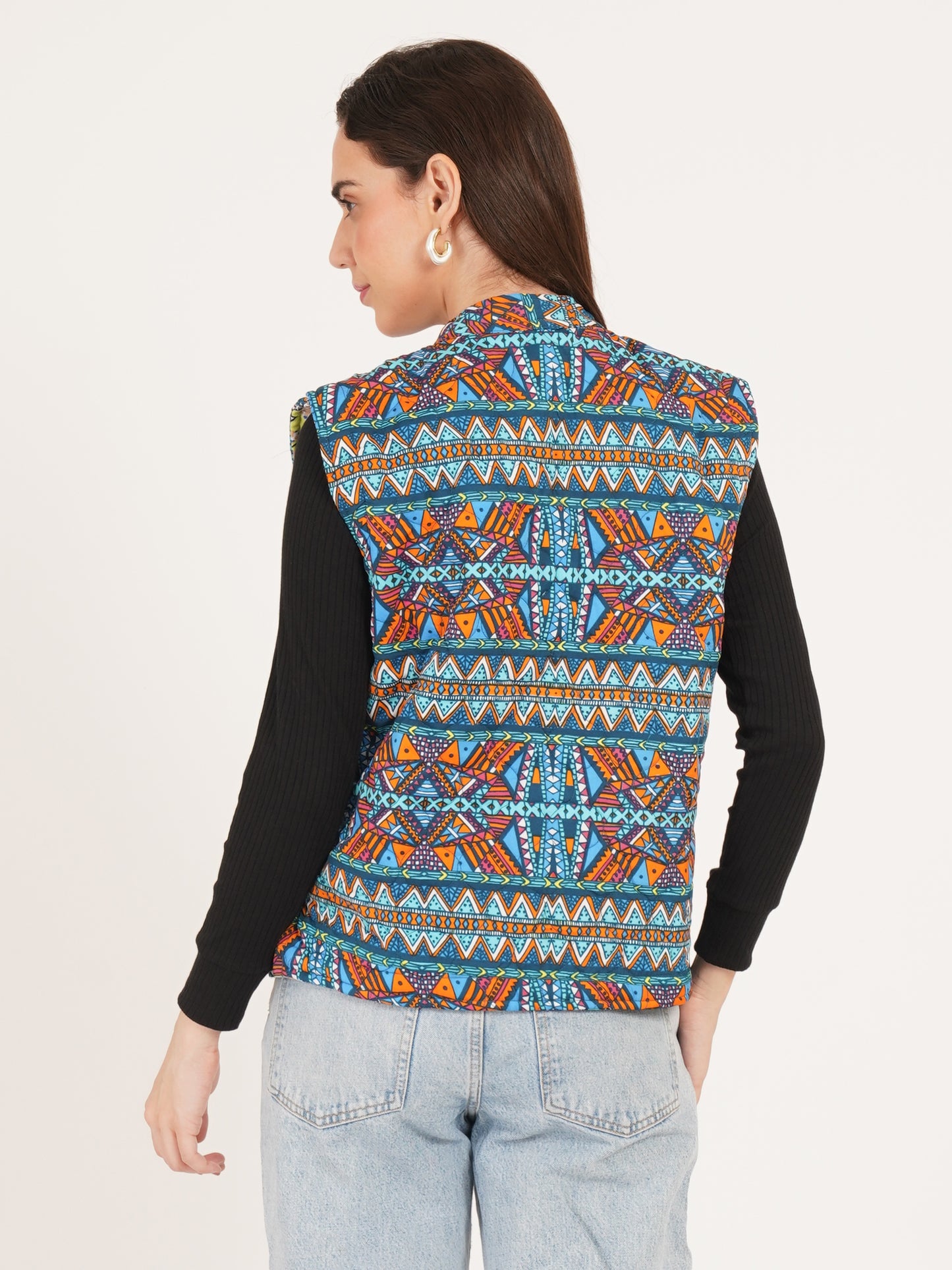 Person wearing reversible jackets a colorful patterned vest on a plain background