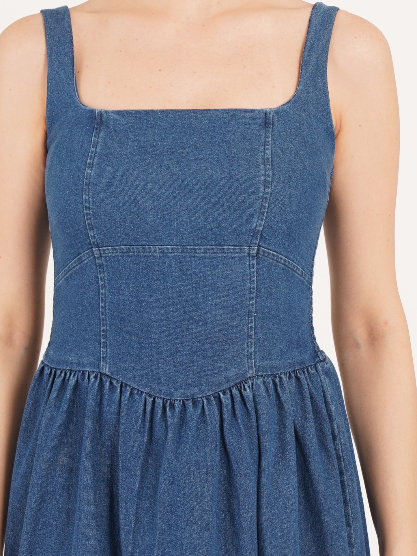 Women dress close look of style develop with fine stitch in blue denim colors gathered at waist.